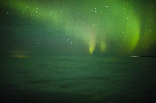 Aurora Boreal vista desde el aire. Volando por encima del mar de nubes 