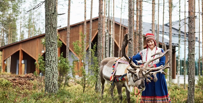 Mujer Sami y reno en el bosque que rodea al hotel Nova Skyland