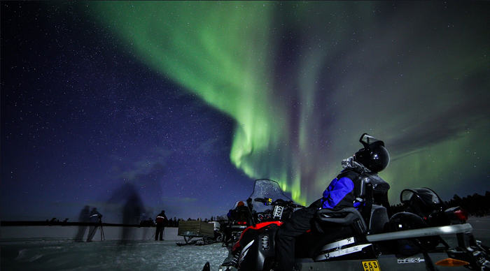 Disfrutando de la visión de la Aurora Boreal durante un safari con moto de nieve en Saariselkä