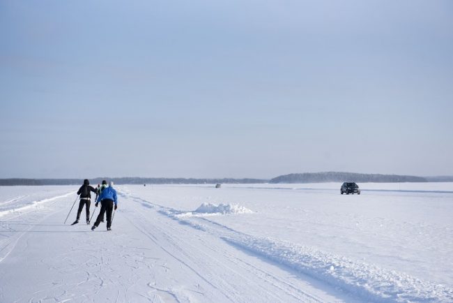 Patinadores y coche en un lago helado del Parque Nacional de Koli 