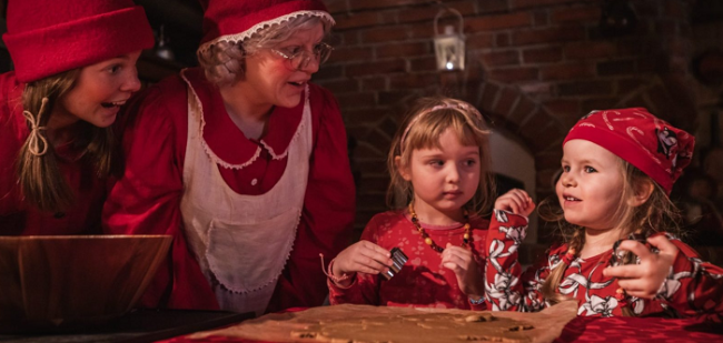 Mamá-Noel-y-un-elfo-enseñando-a-dos-niñas-a-hacer-galletas-de-jengibre_fotoSantaClausVillage